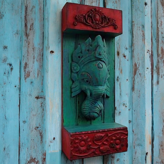 Rustic handcrafted Ganesha wall art in green and red, featuring intricate carvings and a floral base, perfect for traditional Indian home decor.